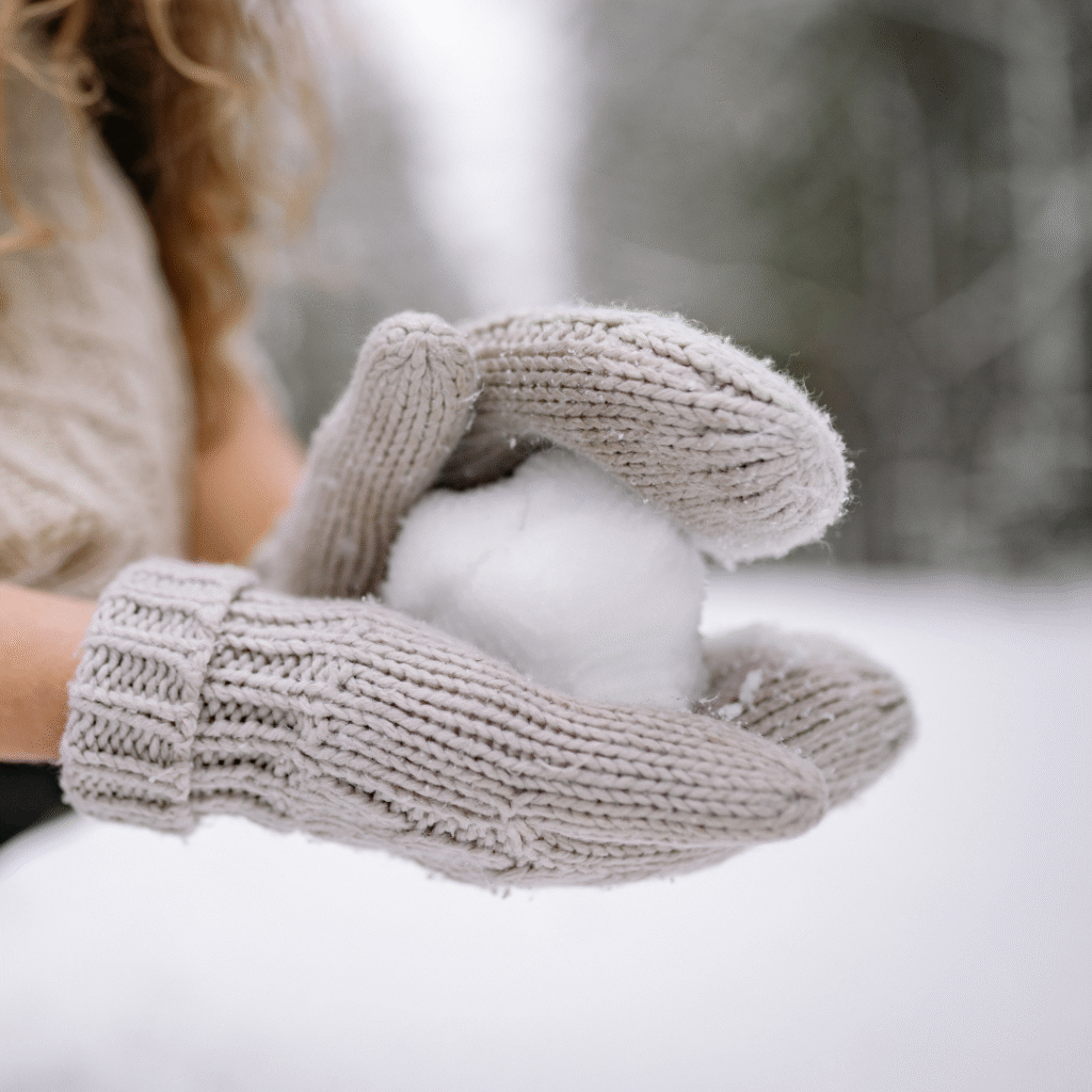 girl holding snowball with mittens on